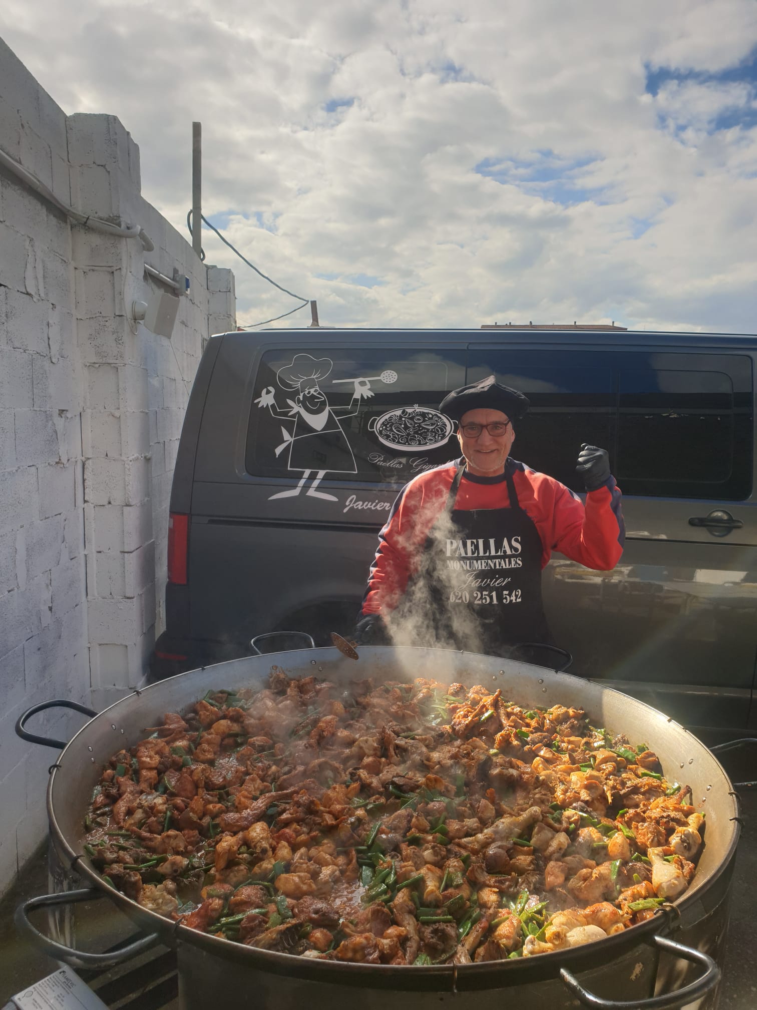 Cocinero de Paellas Monumentales Guiral junto a una paella gigante de carne y verduras, ideal para eventos al aire libre.